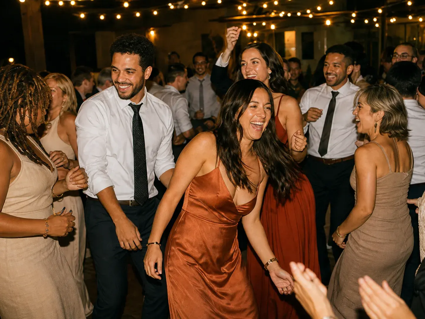 Friends laughing and dancing together at a wedding reception